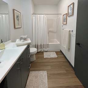 A bathroom with a white sink, toilet, and bathtub with a white shower curtain.