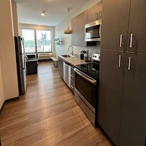 A kitchen with wooden floors and dark brown cabinets.