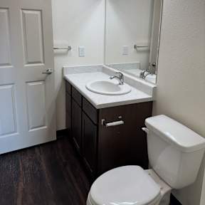 A white toilet sits in a bathroom next to a sink and mirror.