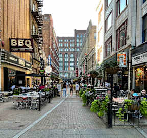 a city street with people walking and tables and chairs