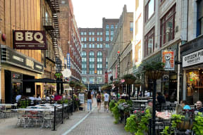 a city street with people walking and tables and chairs