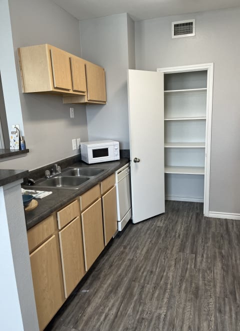 an empty kitchen with wooden cabinets and a sink and a refrigerator