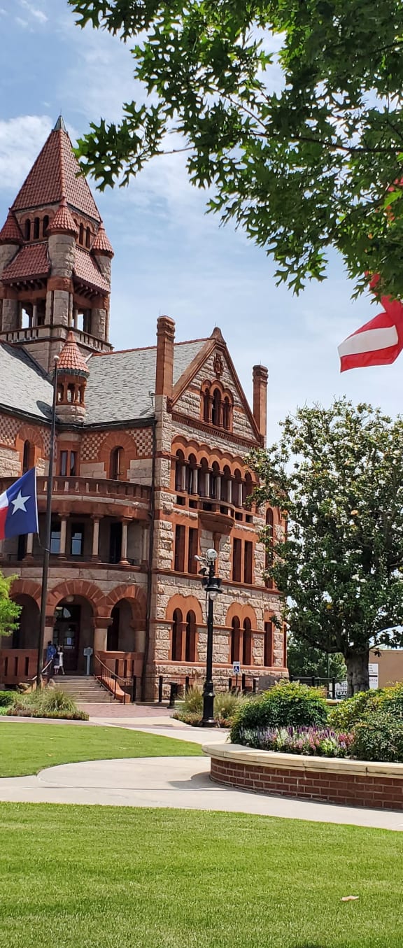 a large brick building with a clock tower and flags on the lawn