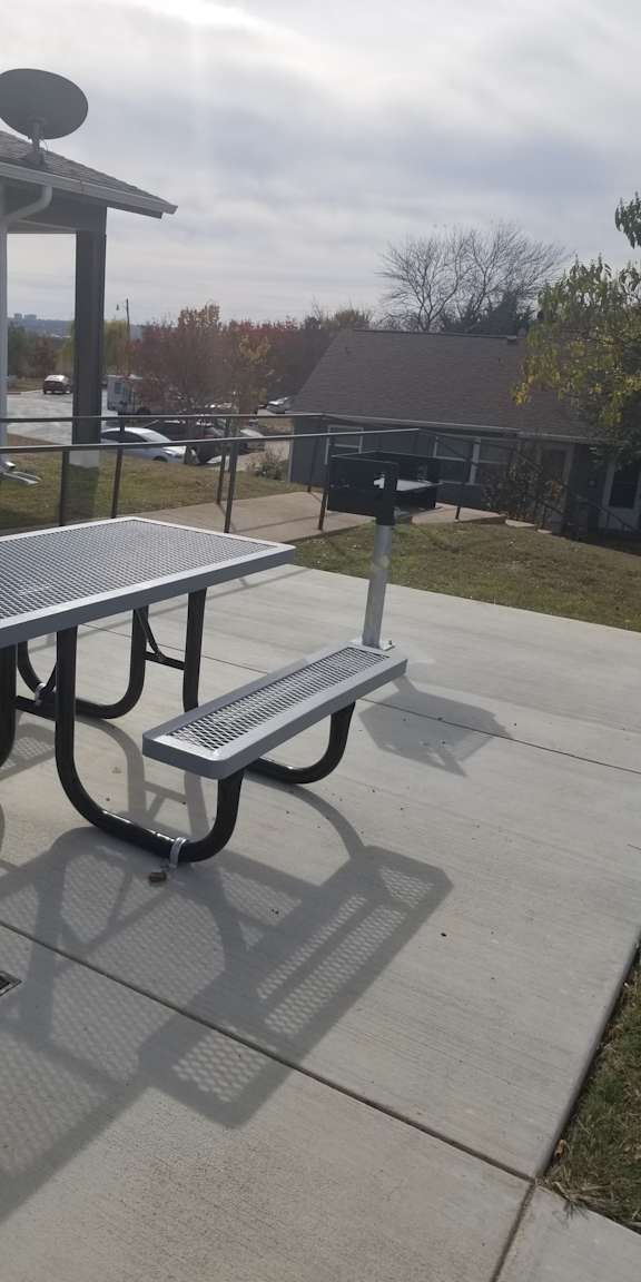 A metal bench with a backrest is on a sidewalk.