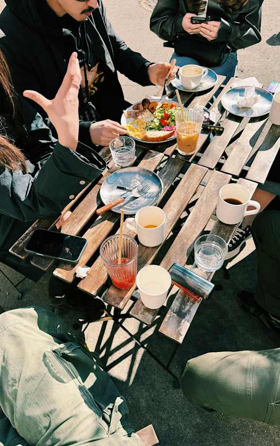 A group of people sitting around a table with food and drinks.