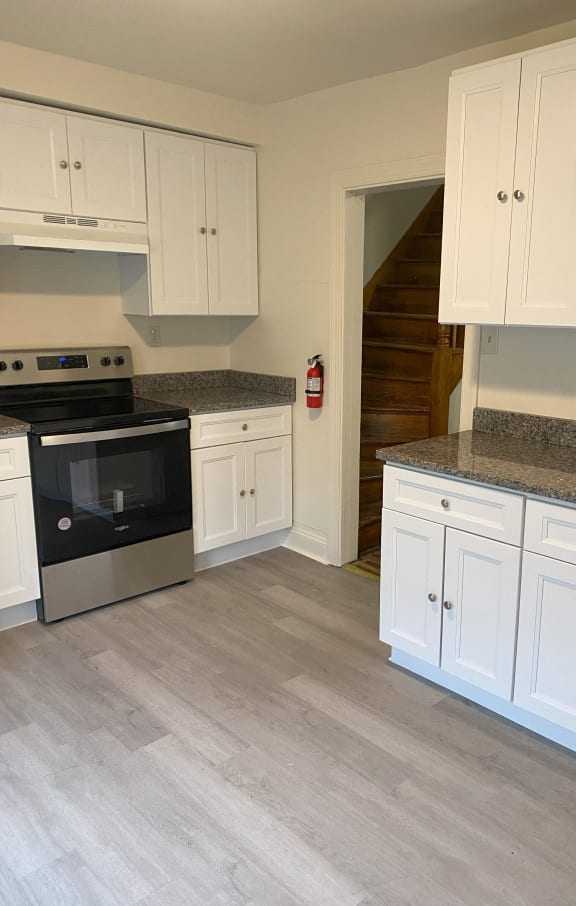 a kitchen with white cabinets and stainless steel appliances and a staircase
