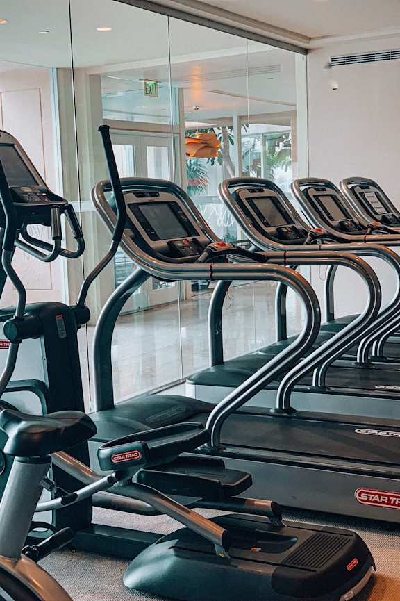 A row of treadmills are lined up in a gym
