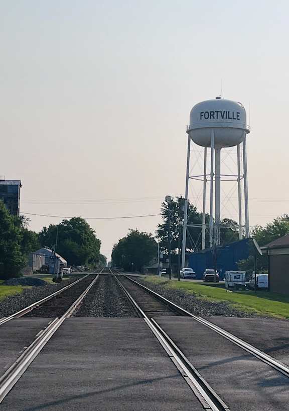 A train track with a water tower labeled Fortville in the background.