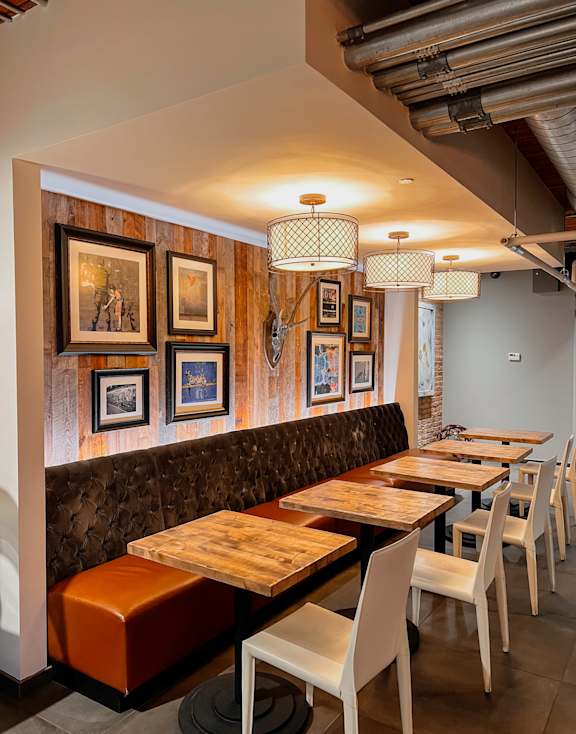 A restaurant with wooden tables and chairs and pictures on the wall.