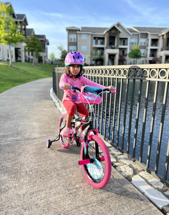 a little girl riding a bike on a sidewalk