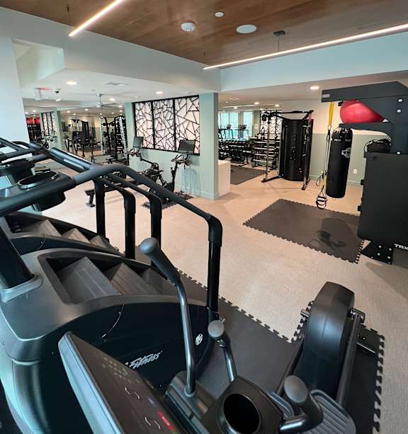 Gym with a variety of equipment including a bench press, dumbbells, and a squat rack at Kessler, Texas, 76137