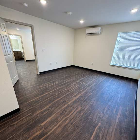 A room with wooden flooring and a window with blinds.