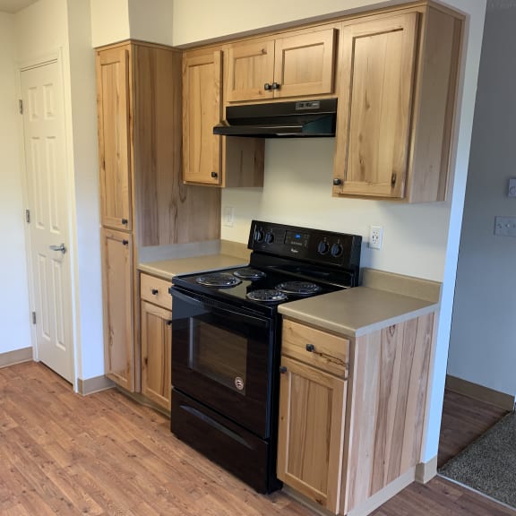 a kitchen with wooden cabinets and drawers and a stove and microwave