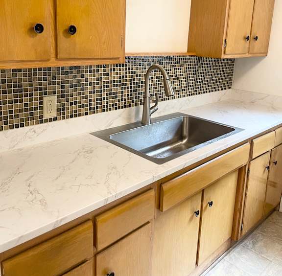 A kitchen with wooden cabinets and a sink.