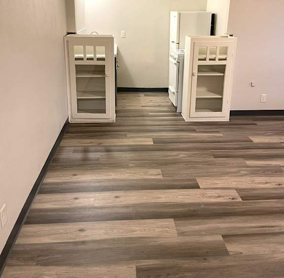 Two white refrigerators are placed in a room with wooden flooring.