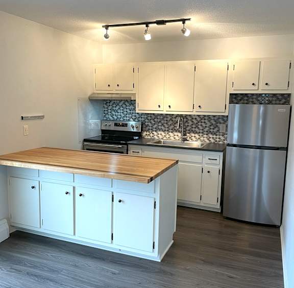A kitchen with white cabinets and a wooden island.