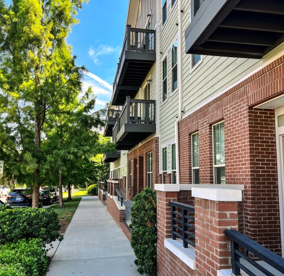 an empty sidewalk in front of an apartment building