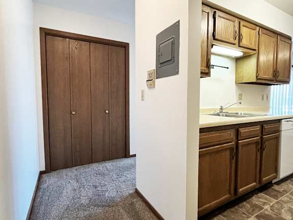 A kitchen with brown cabinets and a white wall.