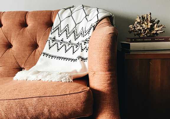 A brown chair with a white and black throw blanket draped over it.