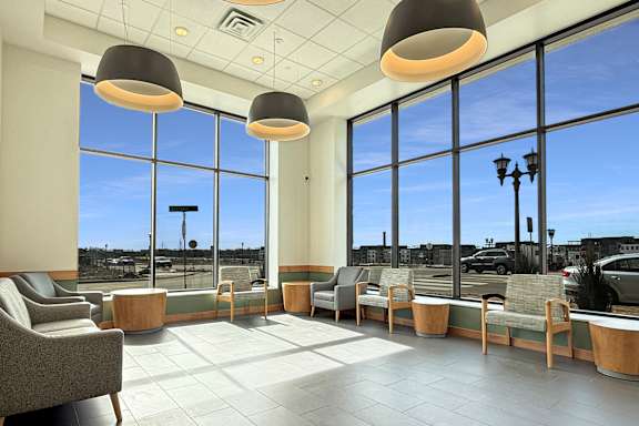 A spacious waiting area with grey tiled floors and large windows.
