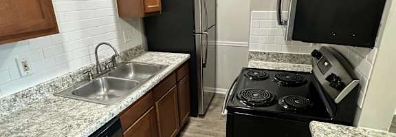 A kitchen with a refrigerator, oven, and dishwasher.