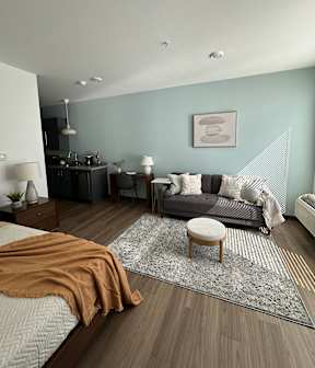 A modern bedroom with a large bed and a grey couch.