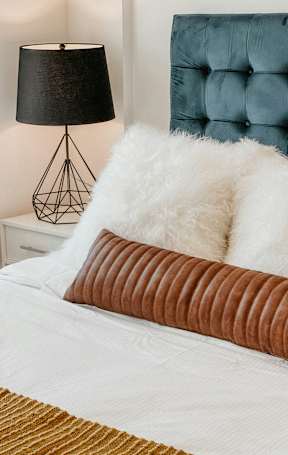 A bed with a white comforter and a brown pillow is in the image.