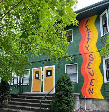 A green building with a mural on the side.