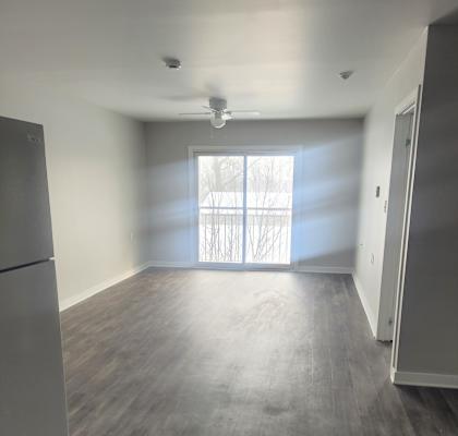 A room with a grey floor and a window with blinds.
