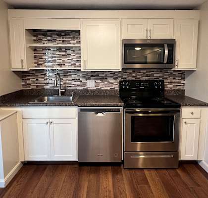A kitchen with white cabinets and a black stove top oven.