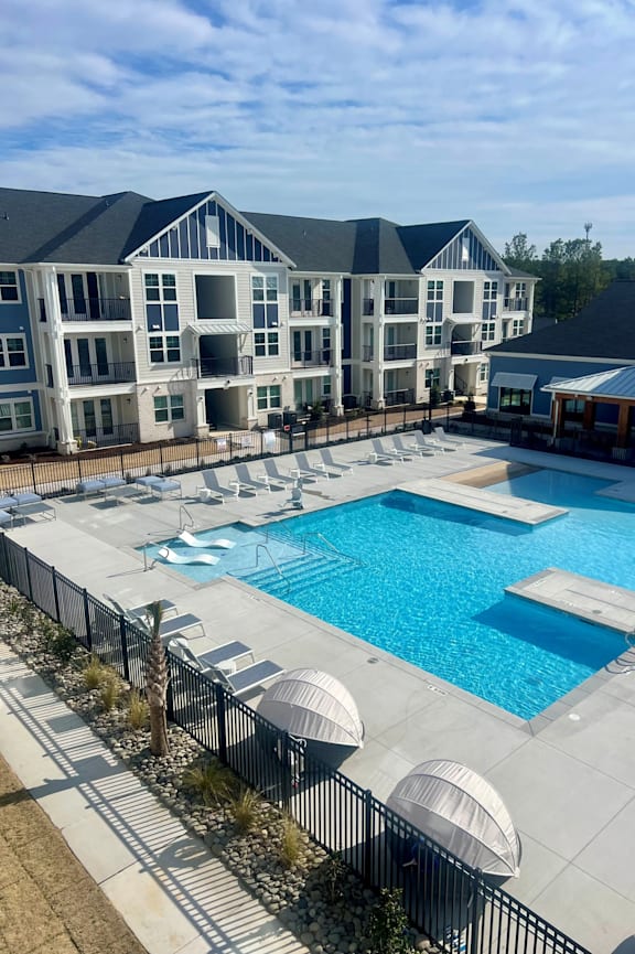 A large swimming pool in front of a multi-story residential building.