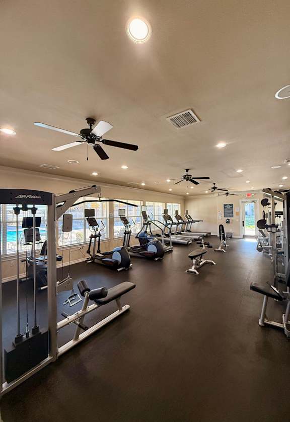 A gym with a variety of equipment including treadmills, weights, and exercise machines.