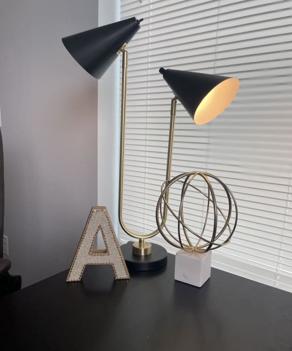 two lamps on top of a black table with a window