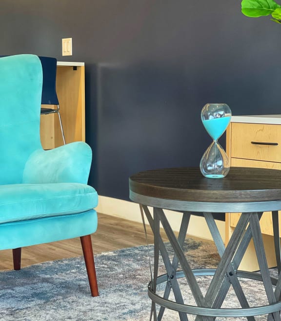a living room with a blue chair and a table with an hourglass on it at 2300 West Apartments, Nevada, 89502