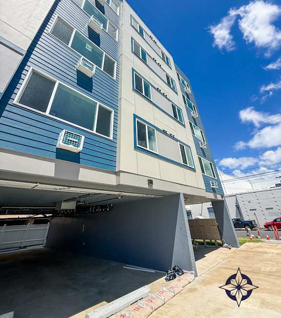 A modern building with a blue and white facade and a clear sky above.