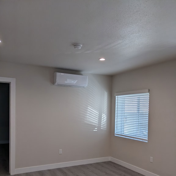 an empty room with a window and a air conditioner