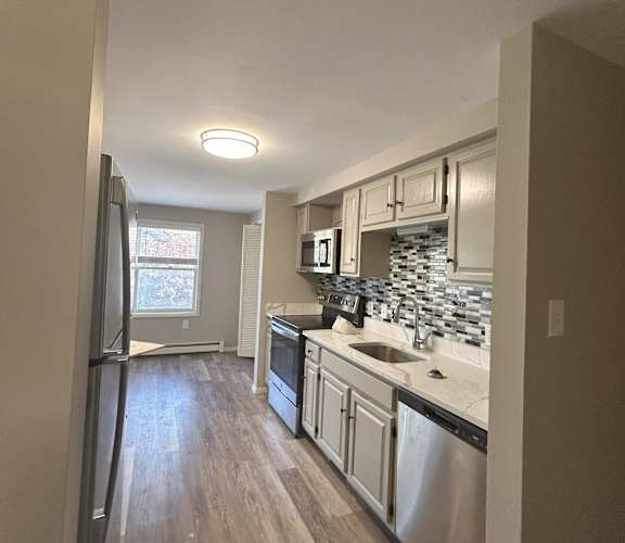 A kitchen with a refrigerator, sink, and cabinets. at Briarcliff at Quechee Apartments, Vermont
