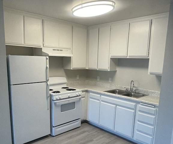A kitchen with white appliances and cabinets.