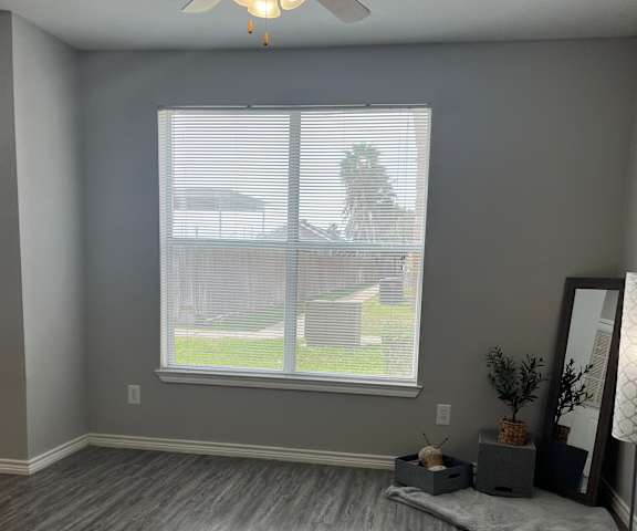 an empty living room with a window and a ceiling fan