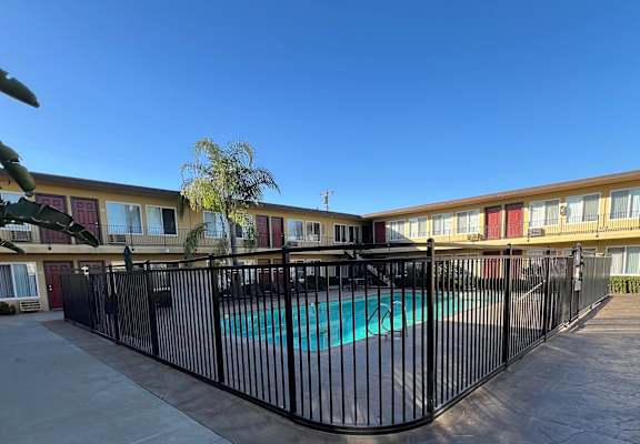 A pool surrounded by a black fence in front of a building.