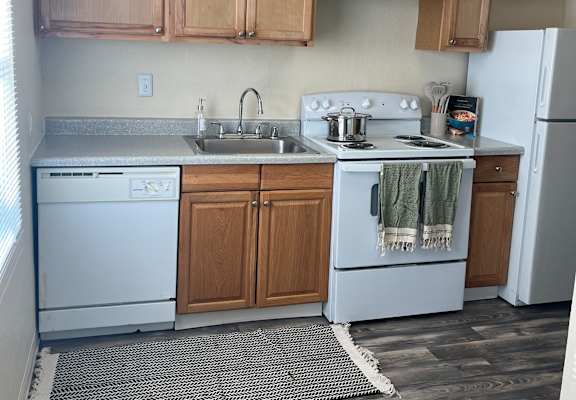 A small kitchen with a white fridge and wooden cabinets.