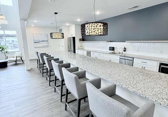 A row of grey chairs are lined up in a kitchen.