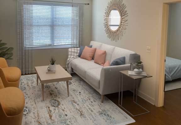 A living room with a white couch, a yellow chair, and a rug.