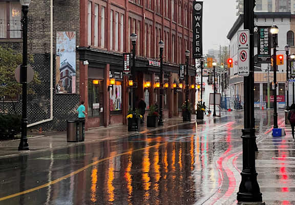 A wet city street with a red building on the left.