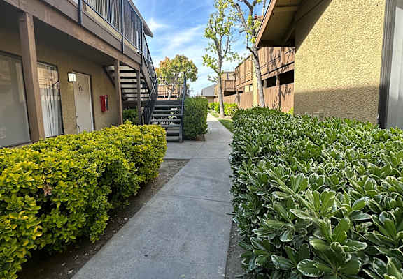 a walkway between two buildings at the whispering winds apartments in pearland, tx