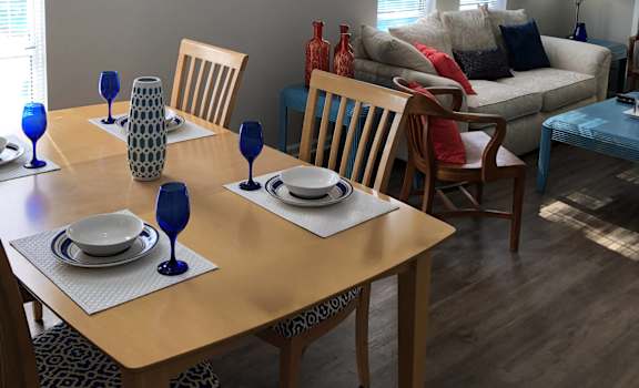 A dining room with a wooden table set for two.