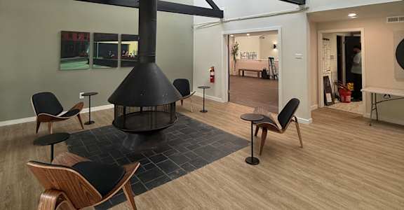 A room with a fireplace and chairs.