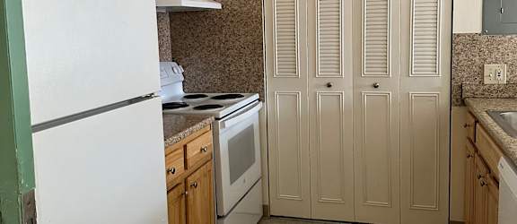 A white cabinet with drawers is mounted on a wall above a wooden table.