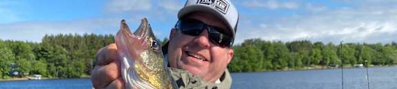 a man holding a fish on a boat on a lake