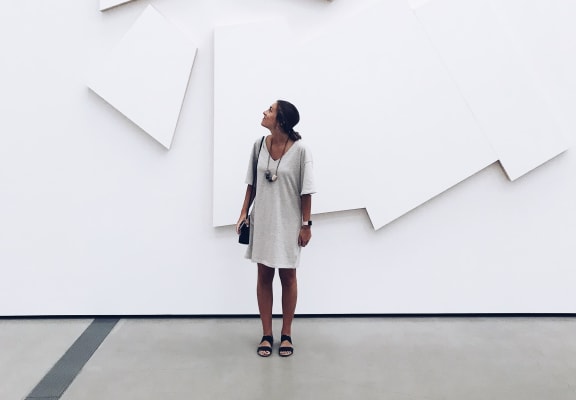 a woman standing in front of a white wall with white shapes hanging on it